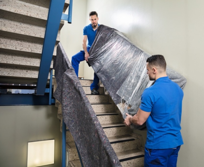 Two Movers Carrying Furniture On Staircase